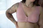 Vrouw met tattoos op linkerarm draagt roze voedingsbeha met 3 drukknoopjes aan de voorkant